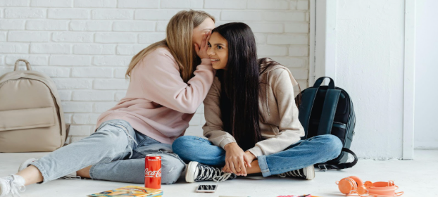 Girls whispering, and sitting on the floor. Image courtesy of kamboompics.
